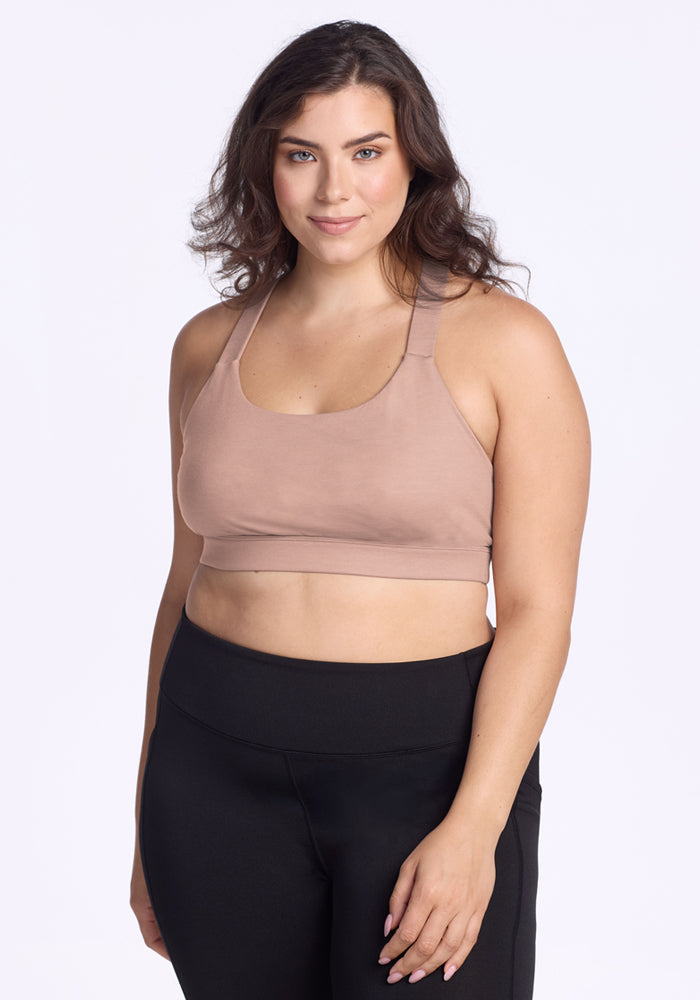 Woman with wavy brown hair models the Woolx Livi Bra in Morning Latte, standing against a plain white background.