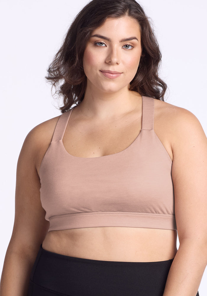 Woman with wavy brown hair in Woolx Livi Bra • Final Sale - Morning Latte, smiling against a light background.