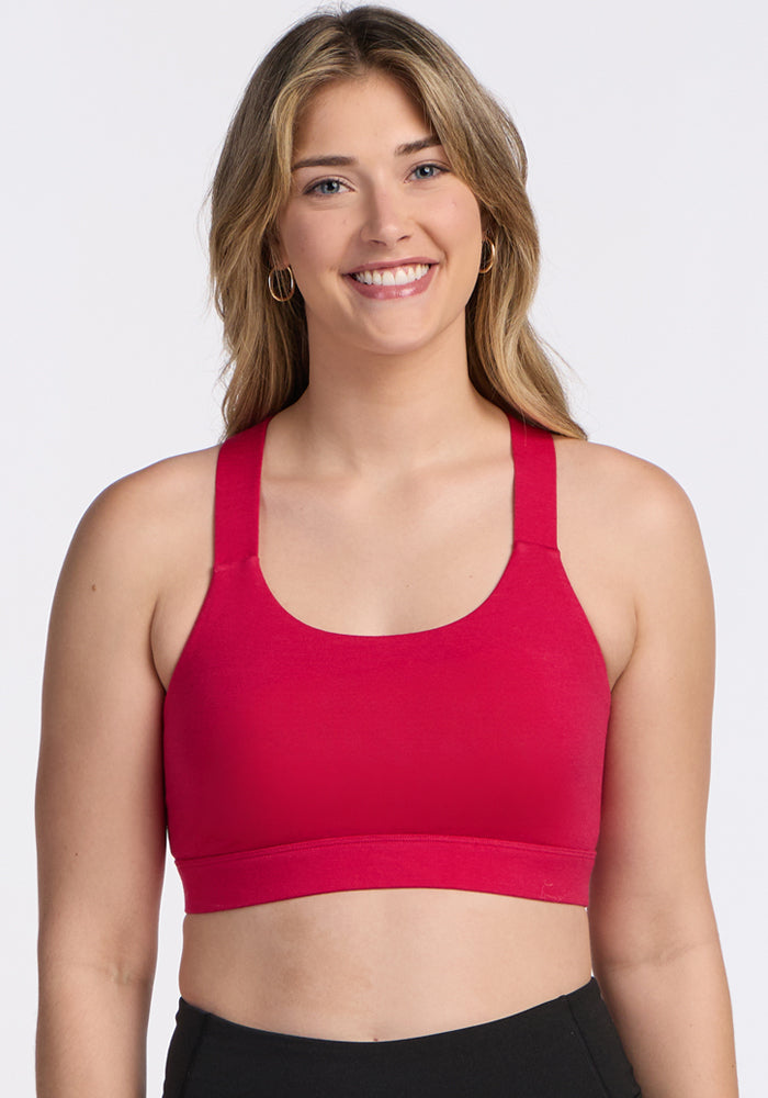Smiling woman in Woolx Livi Bra • Final Sale - Poppy Spark and black pants against a plain background.