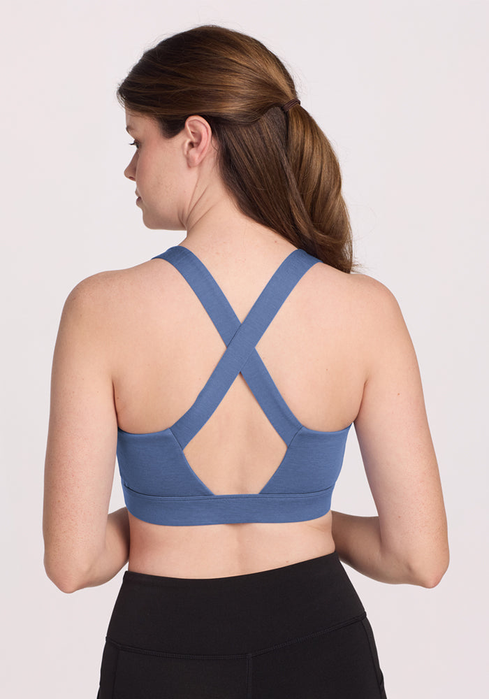 Woman with brown hair wears Woolx Livi Bra • Final Sale - Skyline and black leggings, facing away from the camera.