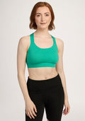 A woman with short brown hair wears the Woolx Livi Bra - Jungle and black leggings against a plain background. | Shea is 5’9”, wearing a size S