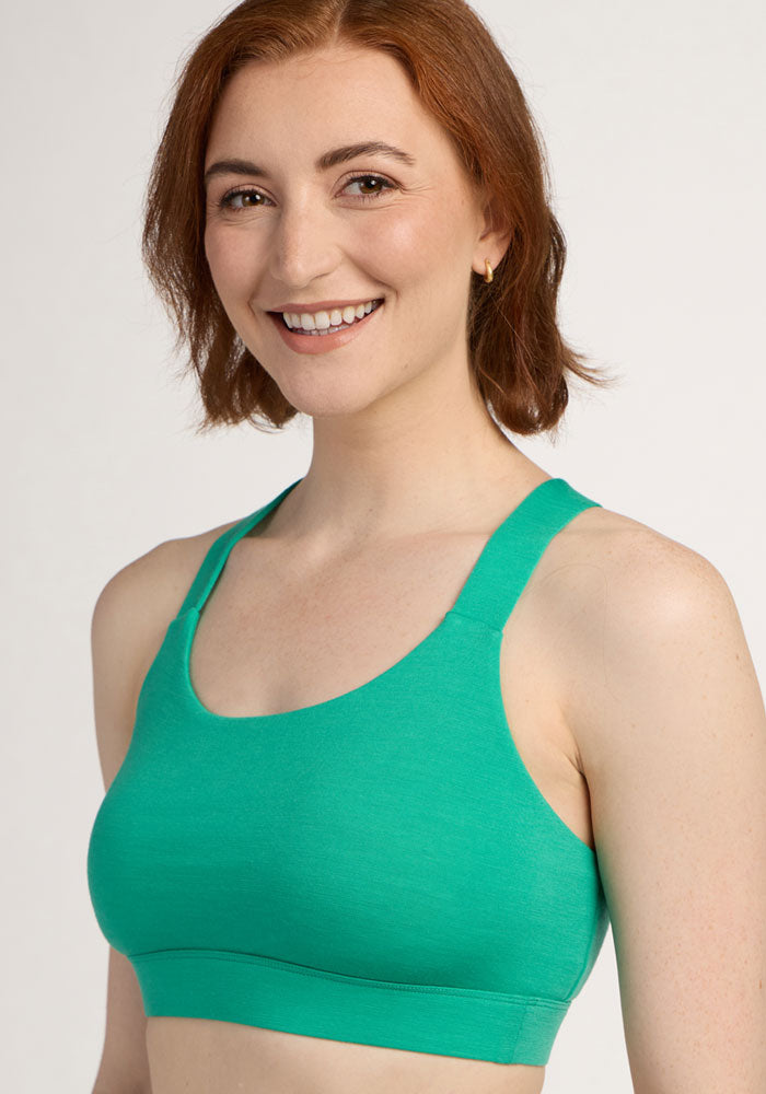 Smiling woman with short auburn hair models the Woolx Livi Bra - Jungle against a plain light background.