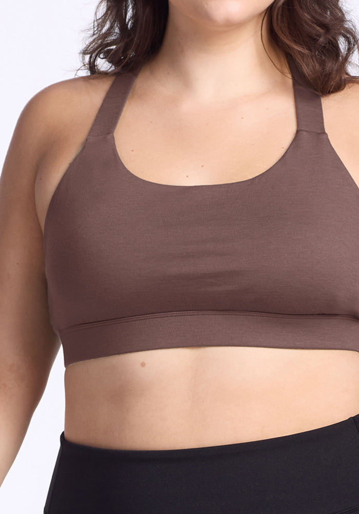 A woman wears the Woolx Livi Bra in Peppercorn with black bottoms, shown from shoulders to waist against a plain background.