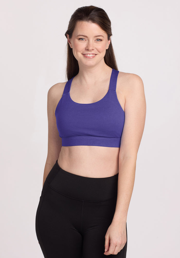 Woman smiling in a Woolx Livi Bra - Berry Indigo and black leggings, standing against a plain light background. | Lilly is 5’9”, wearing a size S