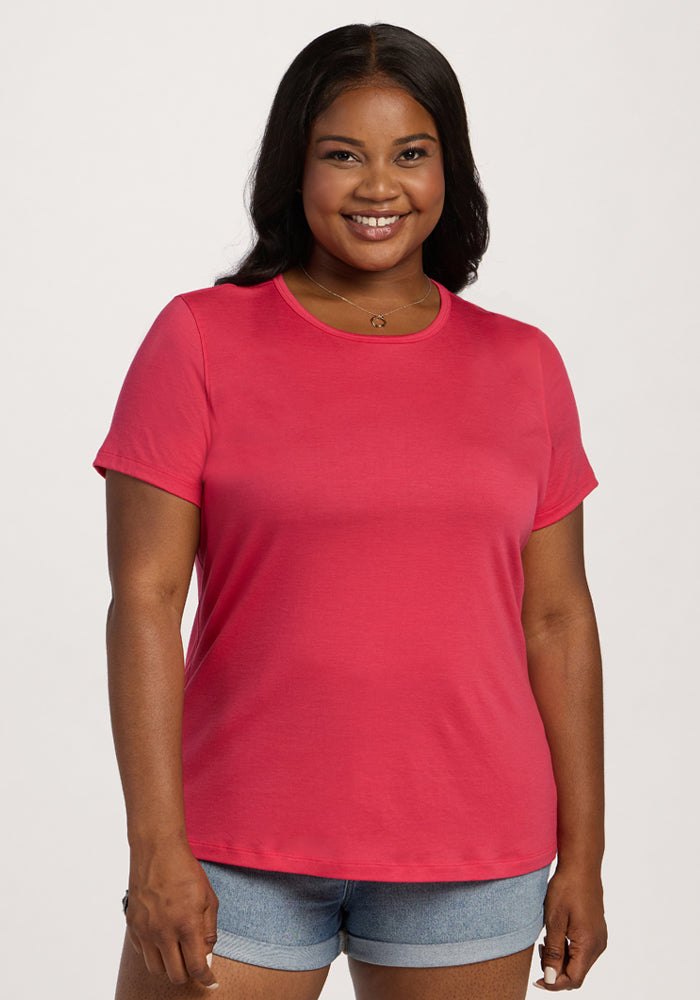 Woman smiling in the Woolx Liza Crew Neck Tee - Berry Ice Pop, paired with denim shorts against a light background. | Sapphire is 5’8”, wearing a size XL