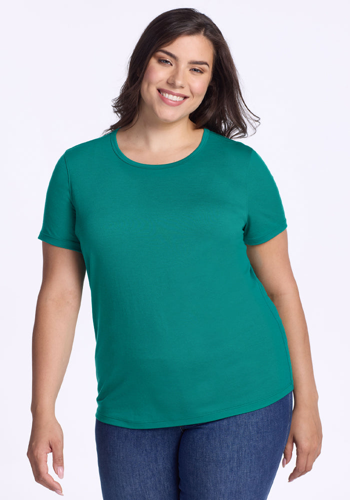 Woman in a Woolx Liza Crew Neck Tee - Cabana Crush and blue jeans smiles against a plain white background. | Juliana is 5'10", wearing a size XL