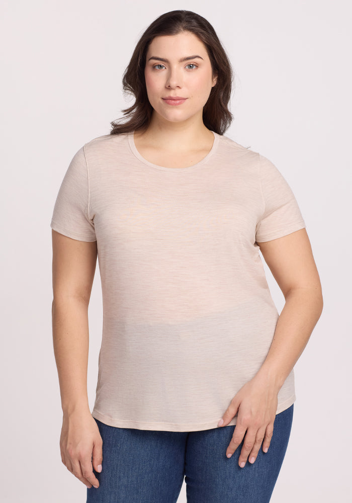 A person with shoulder-length brown hair, wearing a Woolx Liza Crew Neck Tee in Cream Heather and blue jeans, stands against a plain white background, looking at the camera with a neutral expression. | Juliana is 5'10", wearing a size XL