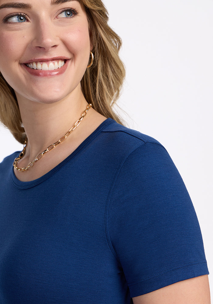Smiling woman in Woolx Liza Crew Neck Tee in Estate Blue, shown from shoulders up against a white background.