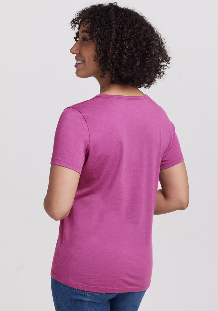 Smiling woman with curly hair, shown from the back, wearing Woolx Liza Crew Neck Tee in Purple Wine and jeans.