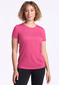 Woman with curly hair wears the Woolx Liza Crew Neck Tee in Raspberry Fizz and black pants against a white background.