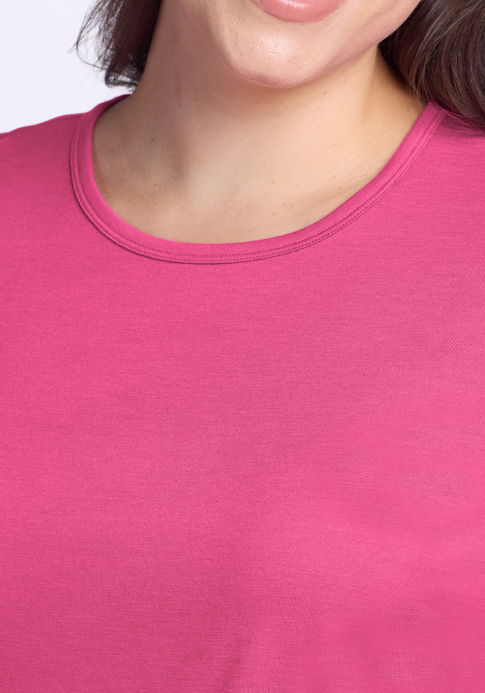 A woman wearing the Woolx Liza Crew Neck Tee in Raspberry Fizz, smiling; only her lower face and upper torso are visible.