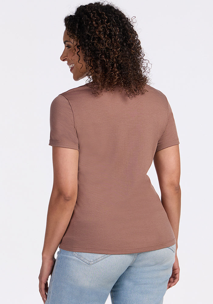 Smiling woman with curly hair wears Woolx Liza Crew Neck Tee in Sienna Kiss and light blue jeans, shown from the back.