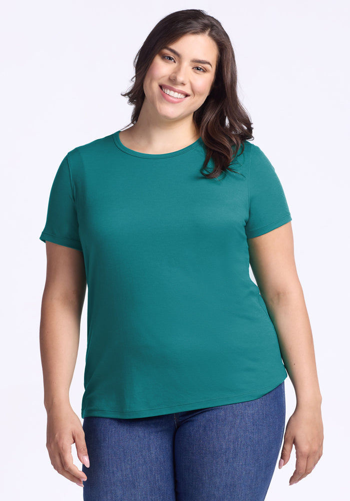 Woman smiling, wearing the Woolx Liza Crew Neck Tee in Surfside and blue jeans, against a light background.