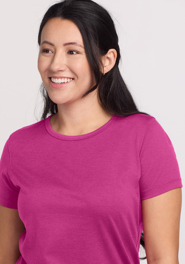 Smiling woman with long dark hair in a Woolx Liza Crew Neck Tee in Summer Sorbet, looking slightly to the side.