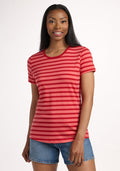 A woman with long dark hair smiles while wearing the Woolx Liza Crew Neck Tee in Wildberry Stripe and denim shorts, standing against a plain white background. | Jade is 5’10”, wearing a size S