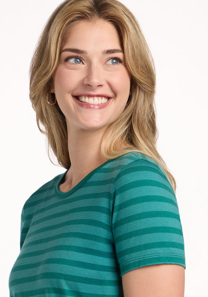 Blonde woman in Woolx Liza Crew Neck Tee - Woodland Stripe, smiling and looking left against a white background.