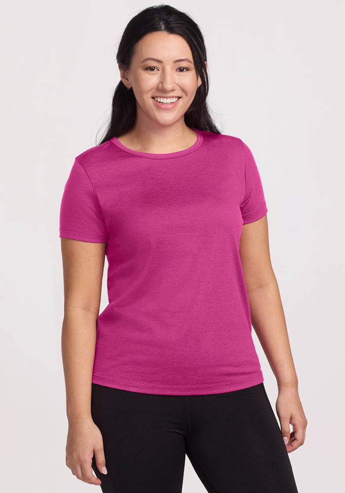 Smiling woman with long dark hair wears Woolx Liza Crew Neck Tee in Summer Sorbet and black pants, light background. | Sarah is 5'8", wearing a size S