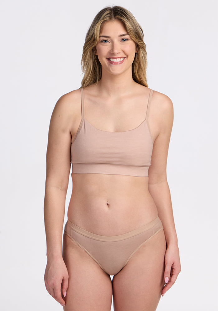 A blonde woman smiles at the camera, wearing the Woolx Luna Bralette in Morning Latte with matching underwear, standing against a simple light background. | Ariana is 5'11", wearing a size S