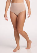 A person wearing Woolx Mabel Full Coverage Underwear in Sand stands barefoot against a plain white background, highlighting the seamless comfort. The image showcases the body from shoulders to feet.