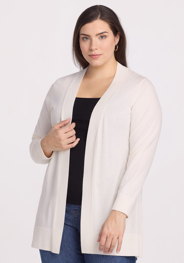 A person with long brown hair is wearing the Woolx Macie Sweater in Dewdrop Pearl over a black top and blue jeans. They have a neutral expression and are standing against a plain white background. | Juliana is 5'10", wearing a size XL