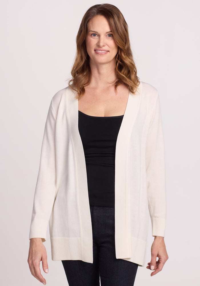 A woman with shoulder-length brown hair wears the Woolx Macie Sweater in Dewdrop Pearl over a black top and dark jeans. Against a plain white background, she smiles slightly at the camera. | Toni is 5’11”, wearing a size S