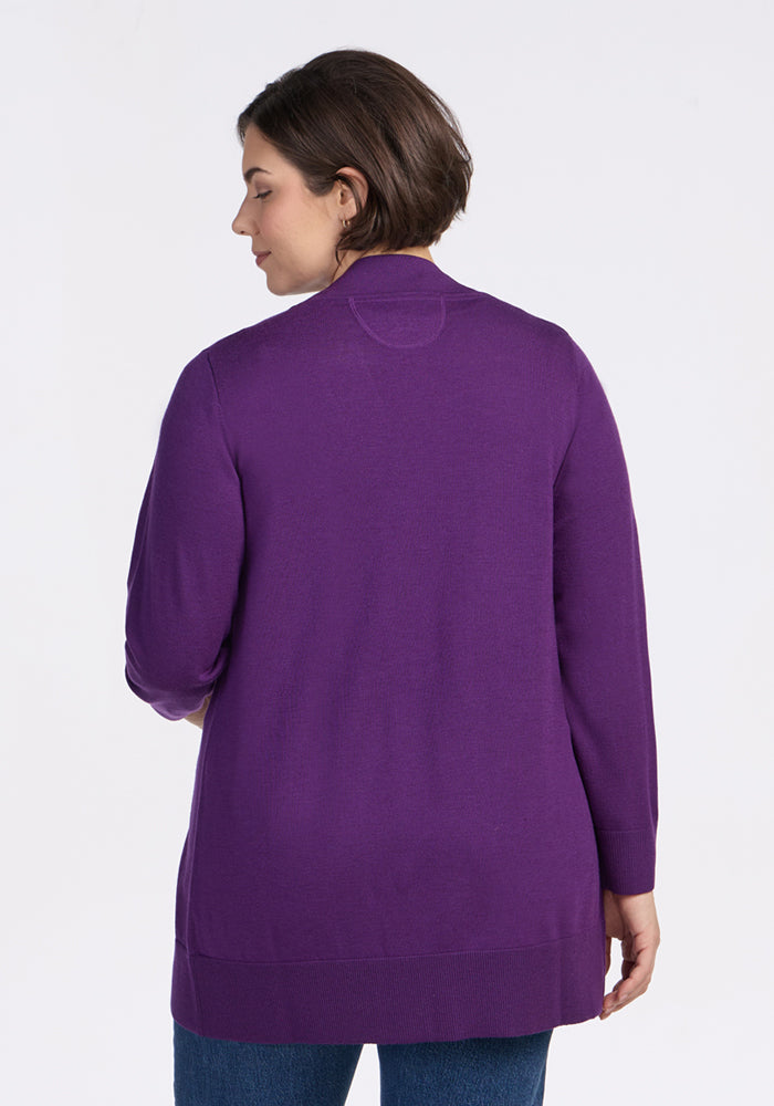 A person with short brown hair is shown from the back, wearing the Woolx Macie Sweater in Plum Crush and blue jeans, standing against a plain white background.