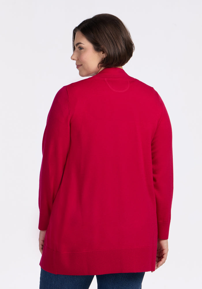 A woman with short brown hair, wearing the Woolx Macie Sweater in Poppy Spark, stands with her back to the camera against a plain white background.