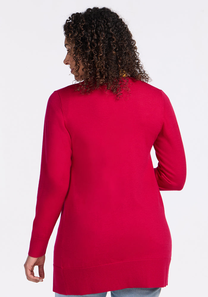 A person with curly hair is shown from the back wearing the Woolx Macie Sweater in Poppy Spark and blue jeans against a plain white background.