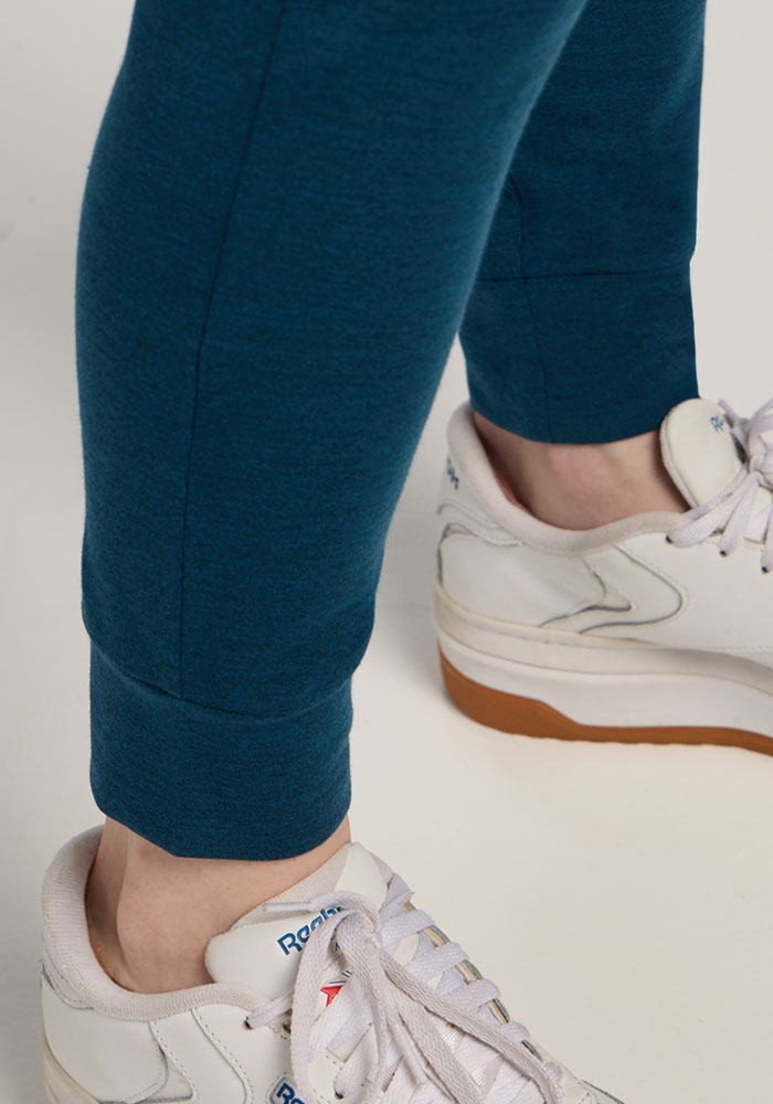 Person wearing Woolx Madden Joggers in Majolica Blue and white Reebok sneakers with gum soles on a light surface.