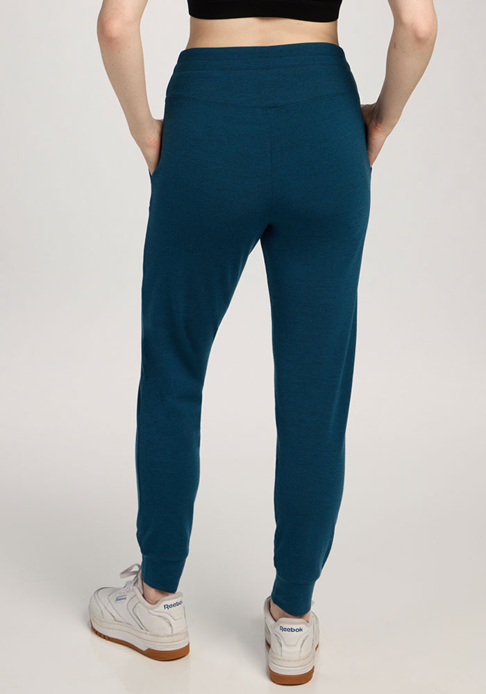 Person wearing Woolx Madden Joggers in Majolica Blue, white sneakers, and a black top, shown from the back.