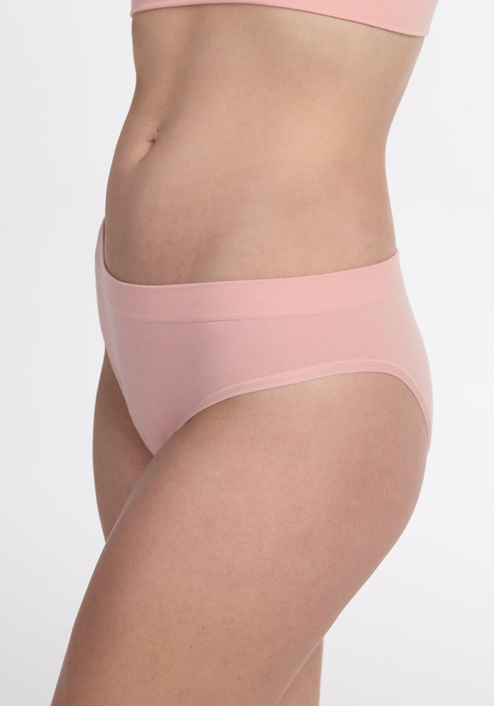 A person wearing the Woolx Maeve Bikini in Rosewater, shown from mid-torso to upper thigh, stands against a plain white background.
