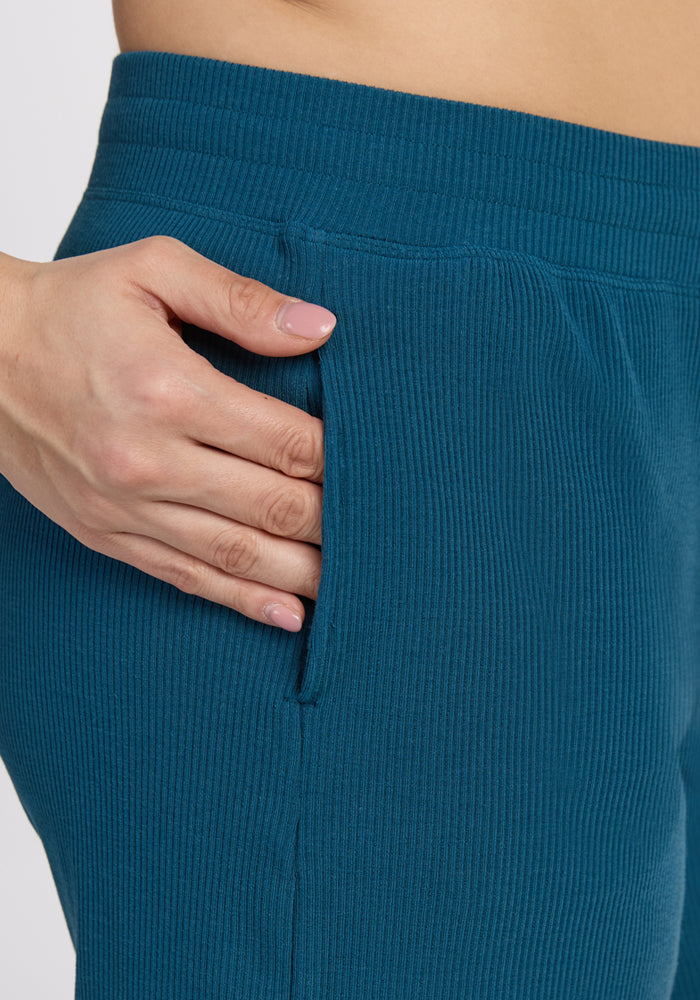 A hand rests in the pocket of Woolx Maisey Ribbed Shorts in Moroccan Blue, shown in a close-up side view.