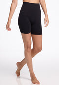 A person stands barefoot against a white background, wearing Marley Shapewear Shorts - Black by Woolx. The high-waisted biker shorts are seamless, form-fitting, offer tummy control, and reach mid-thigh.