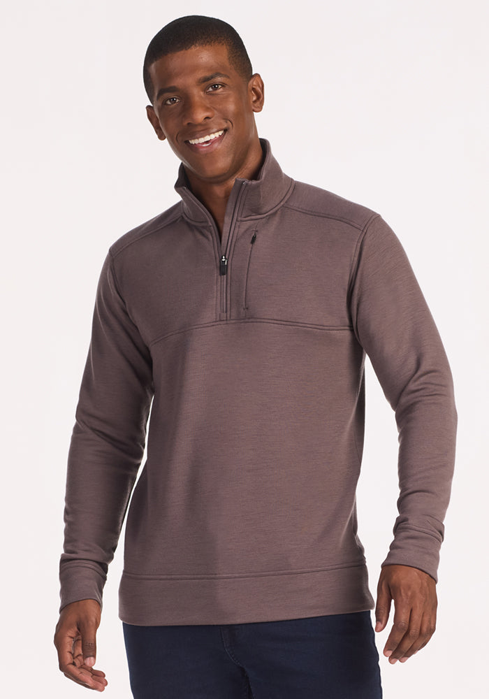 A smiling man wears the Woolx Mason 1/4 Zip in Plum Truffle, featuring a zippered high collar, standing against a plain light background.