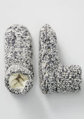 The Woolx Men's Gripper Slipper Bootie in Speckled Stone features cozy knit fabric with a fuzzy Sherpa lining; one bootie stands upright while the other is on its side, revealing the plush interior.