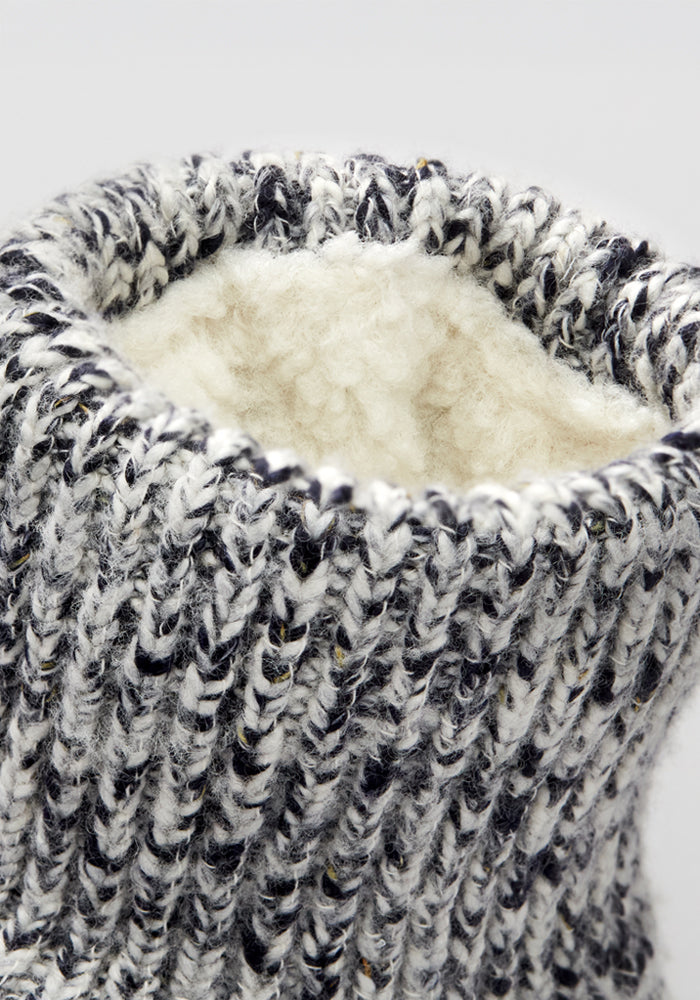 Close-up of the Woolx Men's Gripper Slipper Bootie in Speckled Stone, showing its black, white, and gray knit pattern with a cozy cream Sherpa lining.