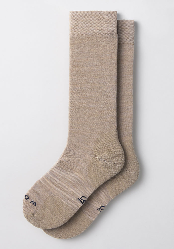 A pair of Woolx Mens Chandler Mid Calf Socks in Simply Taupe are laid flat and overlapping on a plain white background, featuring lightweight fabric, a subtle texture, and small dark text near the toe.