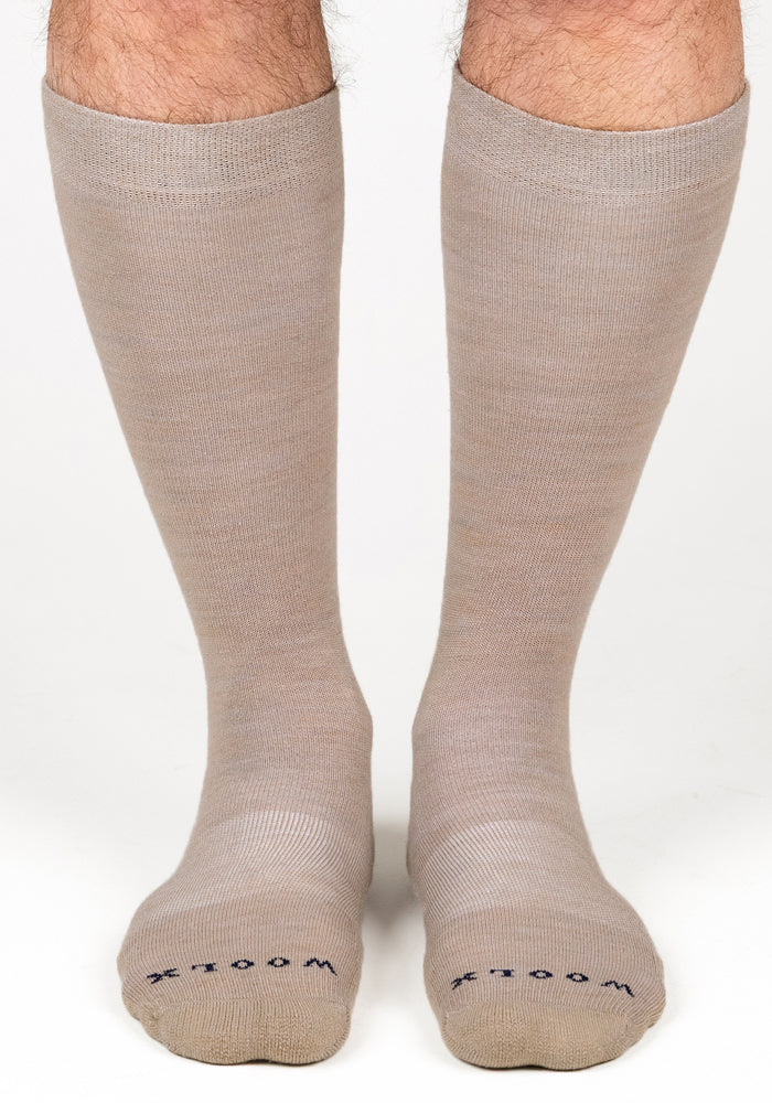 A pair of Woolx Mens Chandler Mid Calf Socks in Simply Taupe, featuring "WOOL" and "X" in dark letters on each toe, shown on feet against a plain white background.