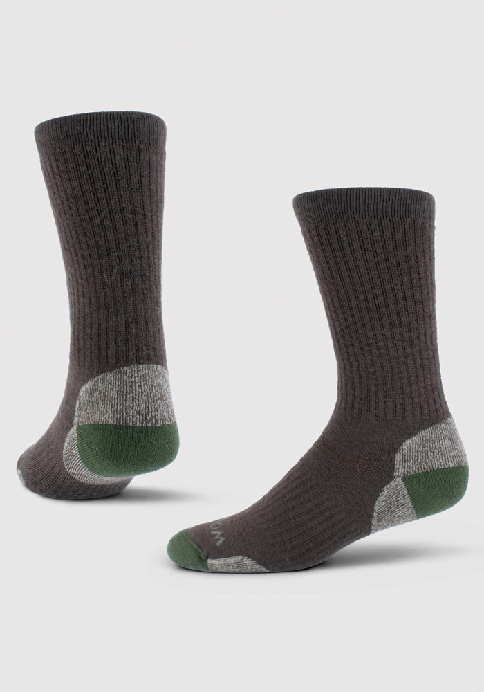 Two Woolx Core Crew Socks in French Roast feature brown ribbed, moisture-wicking Merino wool with reinforced gray and green heel and toe areas. One sock stands upright; the other is angled, both against a plain white background.