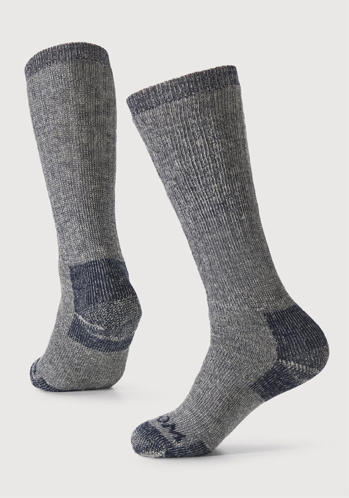 The Woolx Extreme Full Cushion Over the Calf Socks in Navy Carbon are shown against a white background. Made from merino wool, they offer reinforced heels, toes, and cuffs for durability—ideal for cold-weather activities.