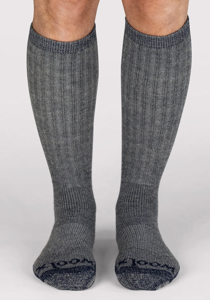 A person wearing Woolx Mens Extreme Over The Calf Socks in Navy Carbon stands on a light background.