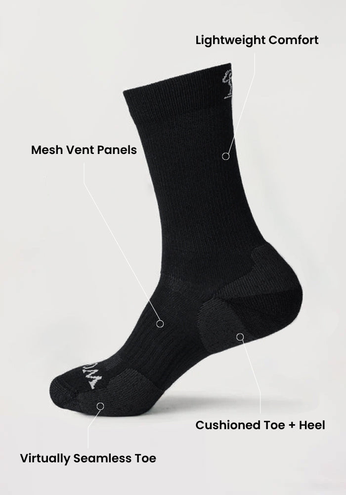 The Woolx Mens Harbor Crew Sock Light Cushion in black offers lightweight comfort, mesh vent panels, a cushioned toe and heel, plus a virtually seamless toe—designed like Merino wool crew socks and shown on a plain light background.
