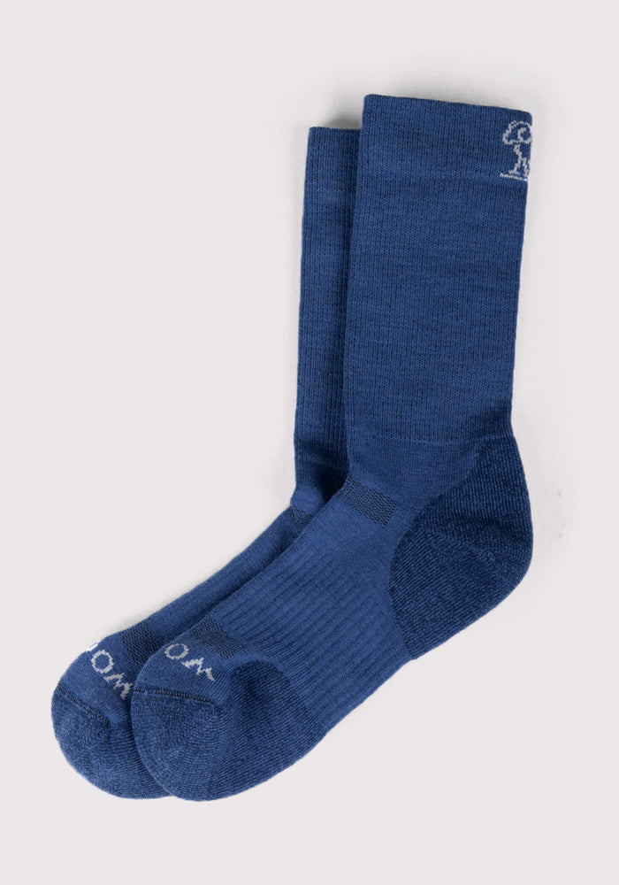 The Woolx Mens Harbor Crew Sock in Sailor Blue features a ribbed Merino wool design, small white embroidery near the top, and white lettering on the toe, displayed on a light grey background.