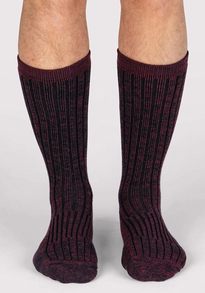 A pair of feet in Woolx Mens Joey Crew Socks - Warm Violet, featuring a ribbed crew style and black and dark red stripes, set against a plain light background.