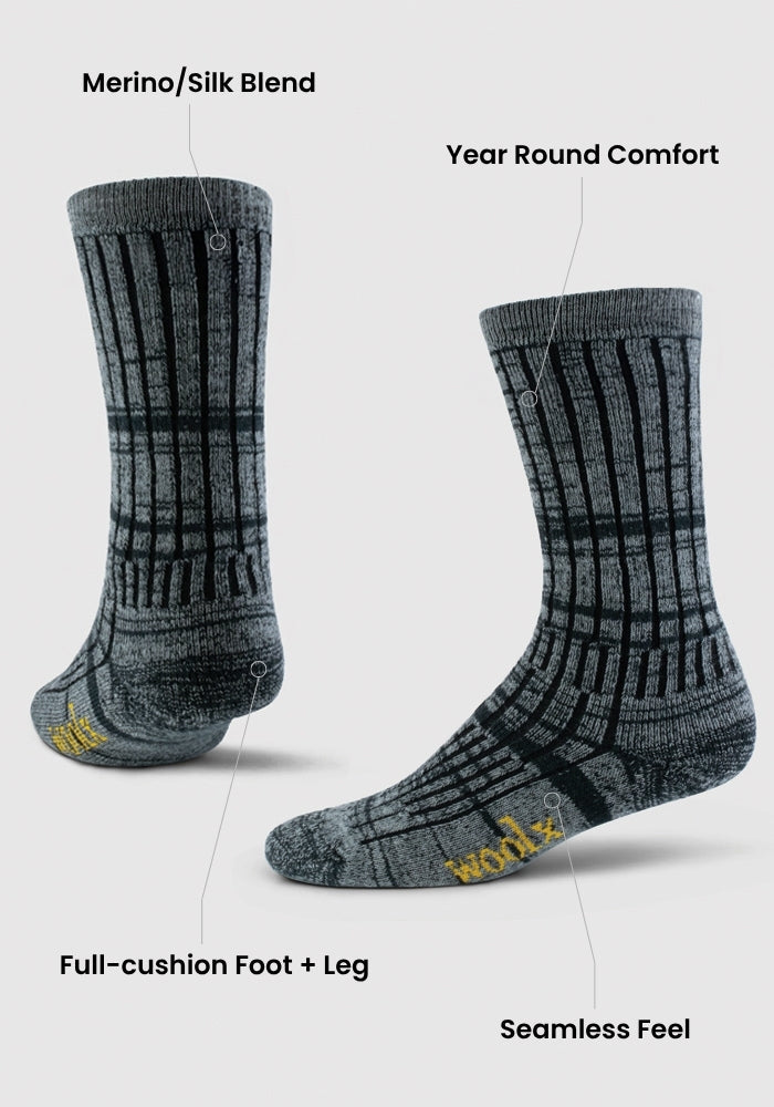 Two dark forest marled mid-calf Woolx socks are shown upright and angled. Features: merino/silk blend, seamless feel, year-round comfort, full-cushion foot and leg. "Woolx" is written in yellow on the toe.
