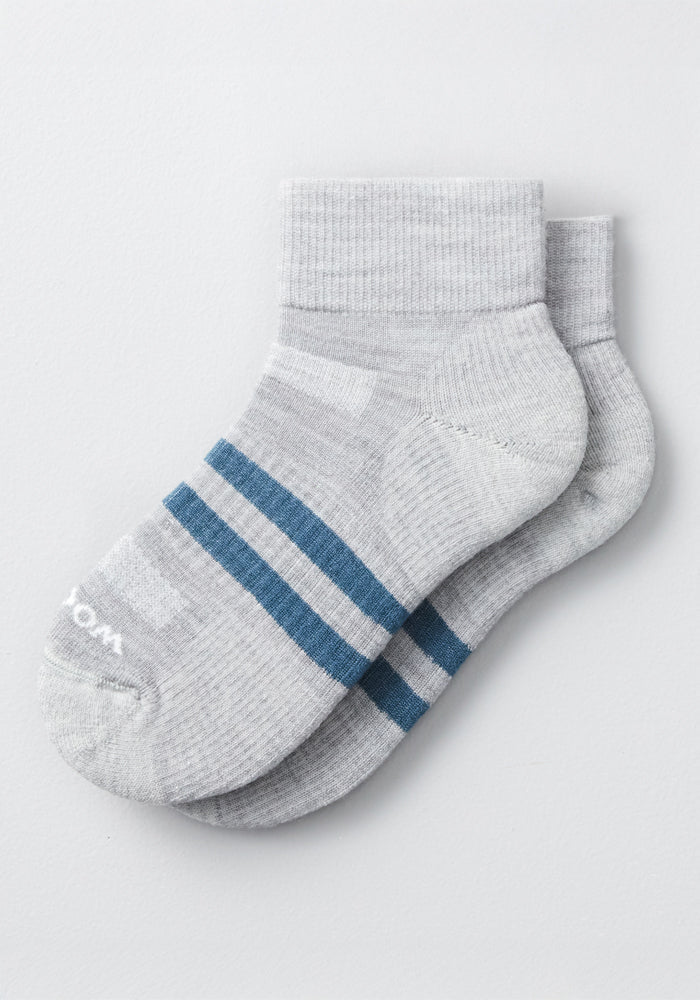 The Woolx Mens Rambler Ankle Sock in grey, featuring two blue stripes and made from moisture-wicking Merino wool, is shown overlapping against a plain white background.