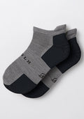 The Woolx Mens Rowan No Show Socks in Pebble, featuring gray fabric with black toe and heel accents, are shown overlapping on a white background.