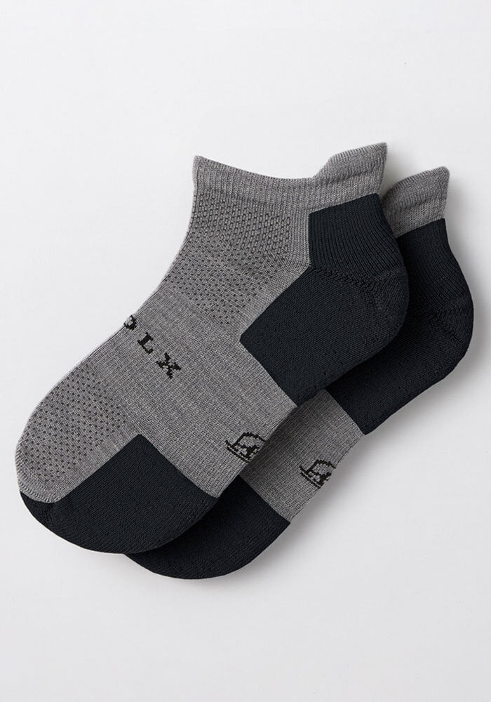 The Woolx Mens Rowan No Show Socks in Pebble, featuring gray fabric with black toe and heel accents, are shown overlapping on a white background.