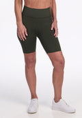 A person wearing Woolx Merino Flex® Dani Bike Shorts in Everleaf and white sneakers stands against a plain white background, with only the lower torso and legs visible. | Tam is 5’8.5”, wearing a size S