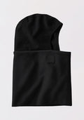 The Woolx Merinoclava in black is a soft, fleece-like balaclava with an extended neck, helmet compatibility, and a rectangular patch near the opening. Laid flat on a light background, it offers excellent cold weather protection.